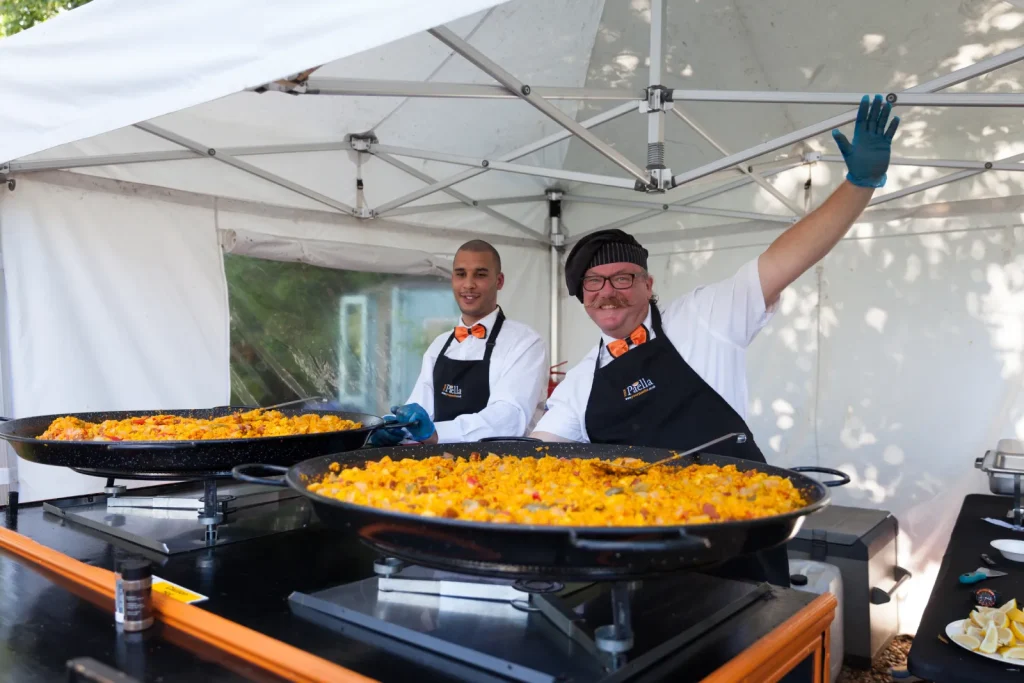 Gary and Dean from your paella behind the paella cart with two full pans of paella
