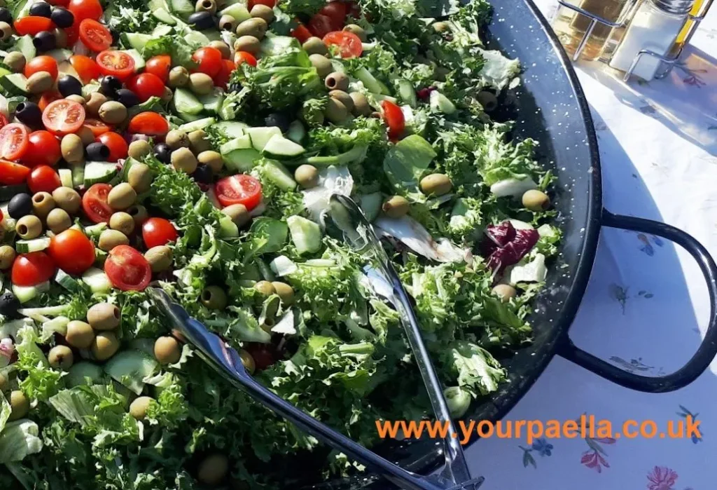 Paella pan filled with a mixed green salad