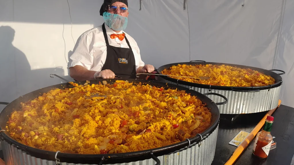 Two large Paella pans full of fresh paella with the paella chef